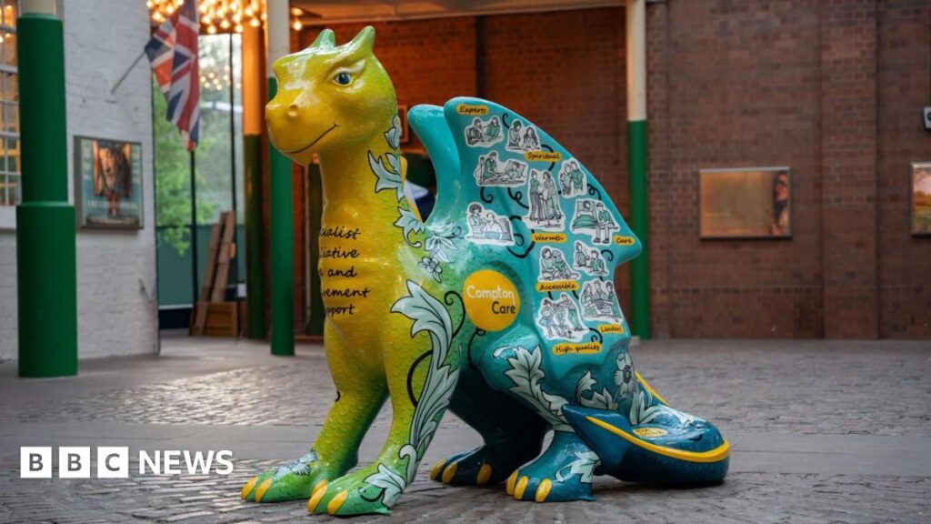 Nine-week dragon sculpture trail to head to Wolverhampton in 2027 A large dragon sculpture that is green, yellow and blue, with yellow claws. It has drawn stickers of people on it, with a yellow circular logo that reads "Compton Care"
