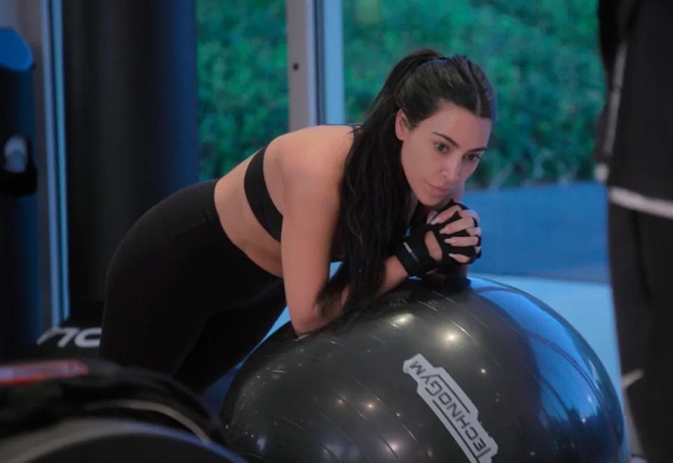 Kim in athletic wear leaning on an exercise ball