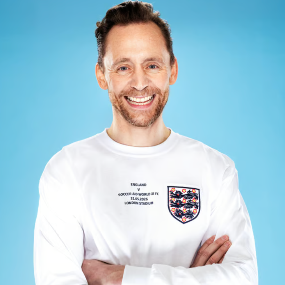 Soccer aid line up person wearing a white longsleeve shirt with a graphic design arms crossed