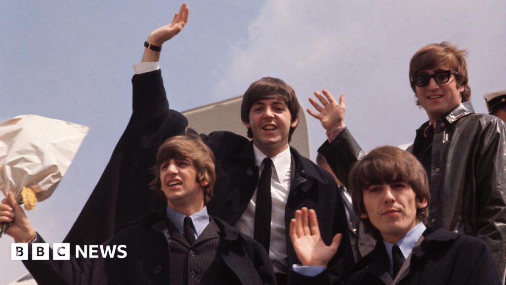 The Beatles wave as they step off an airplane in 1964