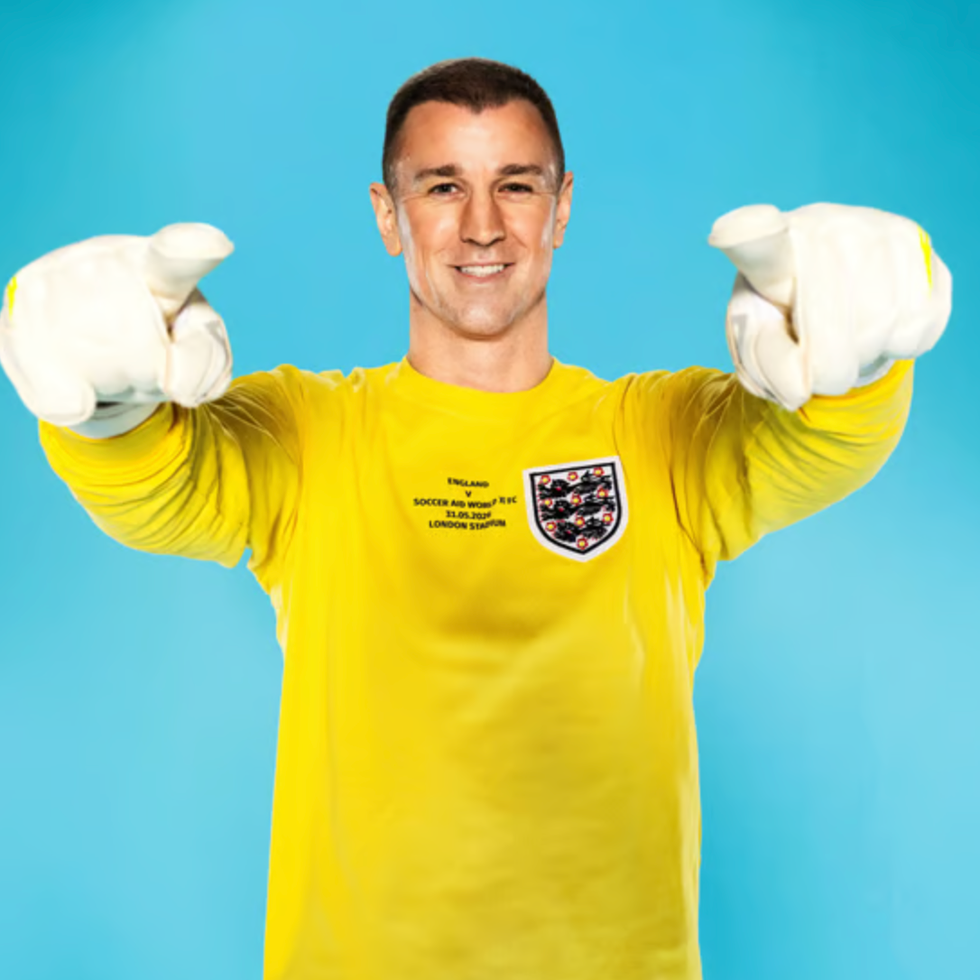 Soccer aid line up person in a yellow longsleeve shirt pointing at the viewer wearing white gloves