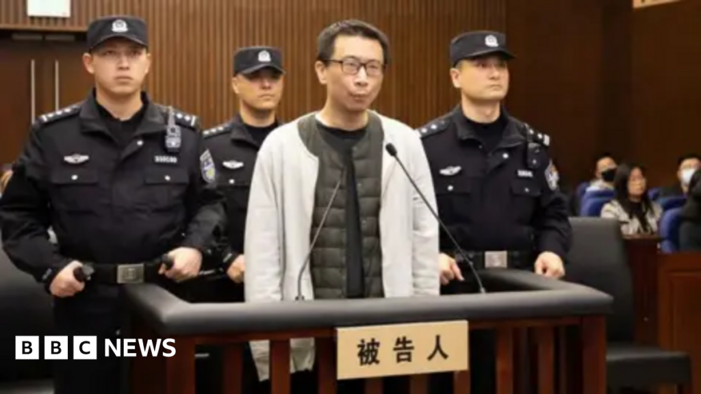 Xu Yao in a white jacket in court, surrounded by guards
