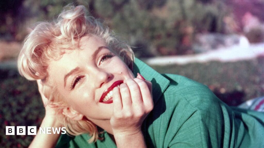 Marilyn Monroe autograph book sells for £3,600 in Surrey Marilyn Monroe with short blonde hair, wearing a green jacket, resting her chin on her hand outdoors with soft background blur.