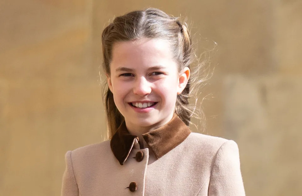 Princess Charlotte smiling in a tan coat