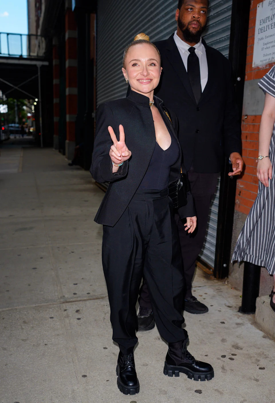 A woman in black flashing a peace sign