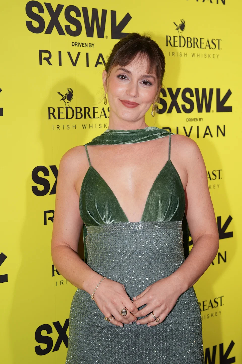 Person in a sleeveless velvet dress with a deep neckline poses at a SXSW event backdrop