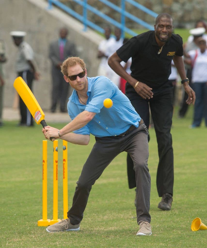 Prince Harry plays cricket as Sir Curtly Ambrose looks on during a Youth Sports Festival