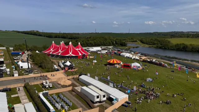 Aerial view of the set up of Big Weekend festival in Sunderland, where you can see a lake and red tents and people waiting outside