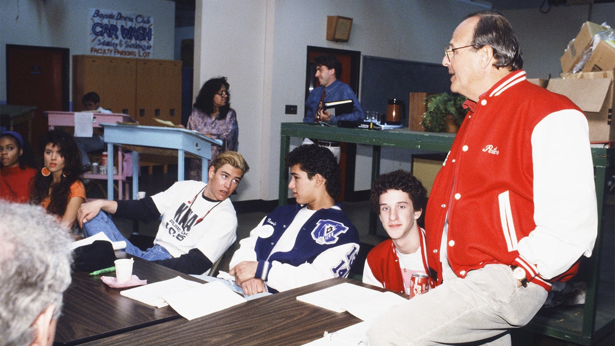 Tiffani Thiessen, Mark-Paul Gosselaar, Mario Lopez, Dustin Diamond, and Peter Engel seated at a table during a read-through