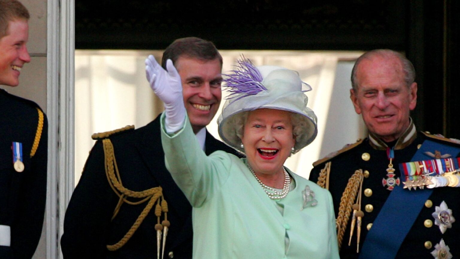 Queen Elizabeth II wears a mint green coat dress and matching hat with pearls and waves from the Buckingham Palace balcony while son ex-Prince Andrew laughs behind her