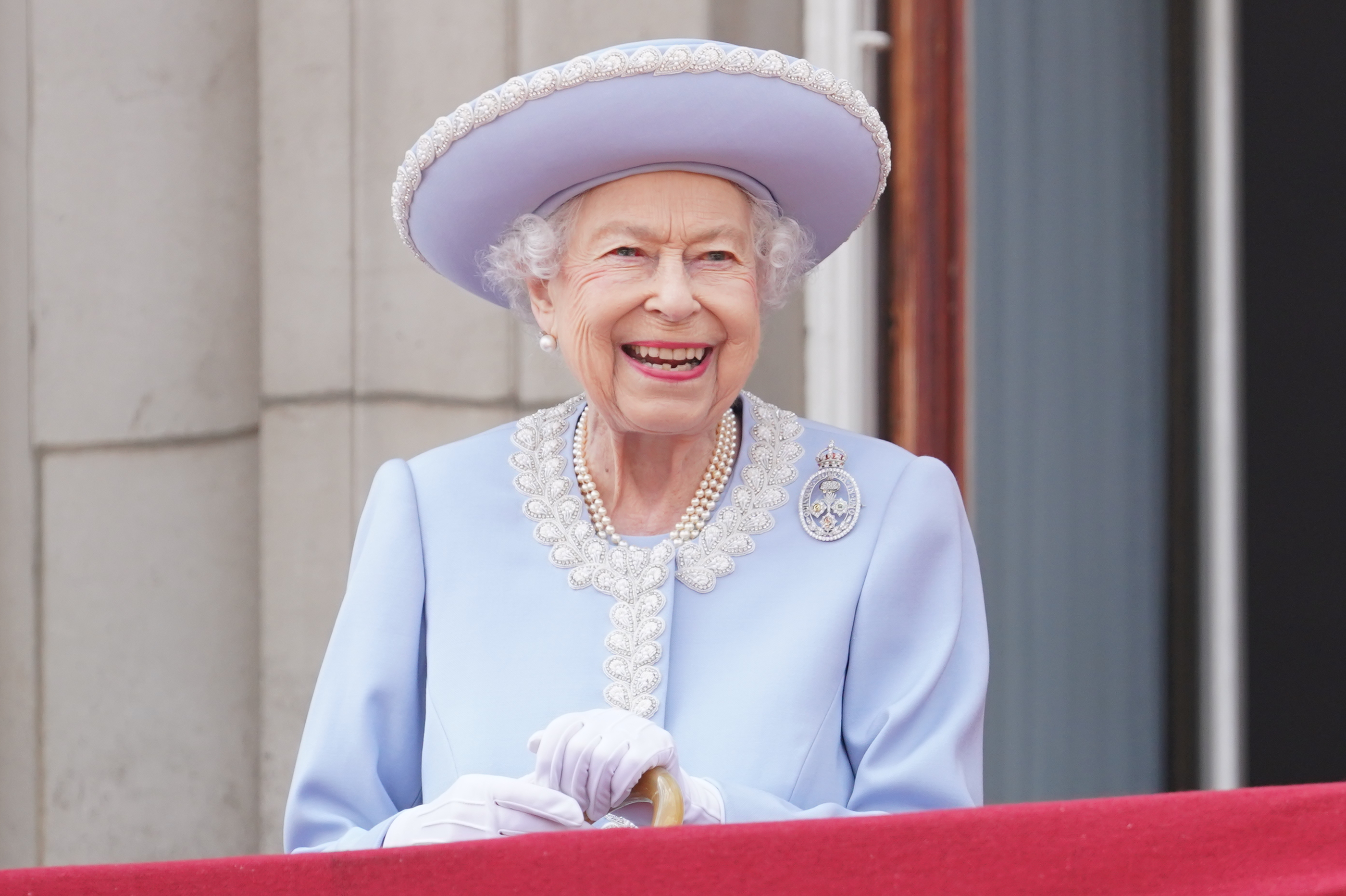 Queen Elizabeth wearing a blue coat and hat smiling during the Platinum Jubilee