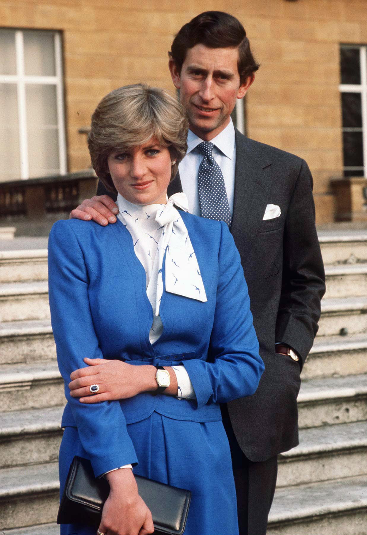Prince Charles wearing a dark suit and Princess Diana wearing a blue suit in their engagement photo