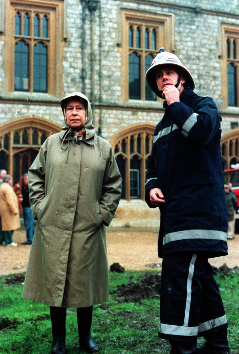 Queen Elizabeth II inspects the ruins of Windsor castle with a fireman, 1992