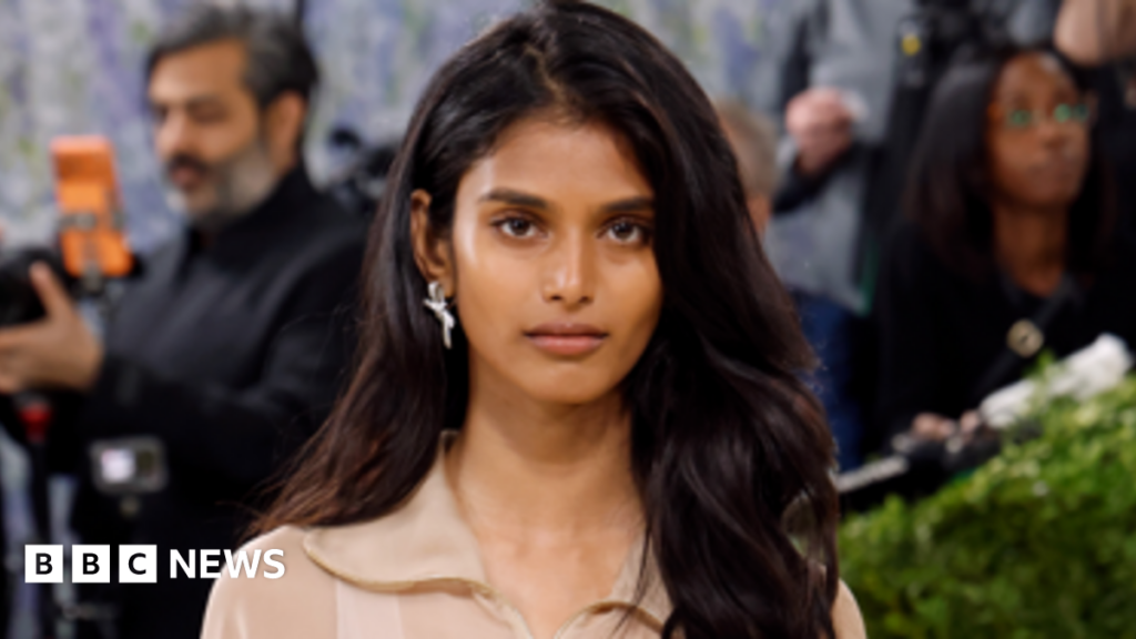 Indian fashion model Bhavitha Mandava presents a creation for the Chanel Cruise 2026/2027 collection in Biarritz on April 28, 2026. She's wearing a black blazer with white detailing on the sides and golden buttons.