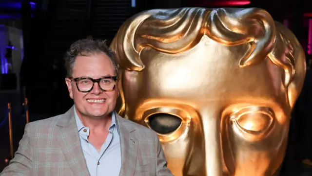 Alan Carr alongside a huge model of a Bafta award