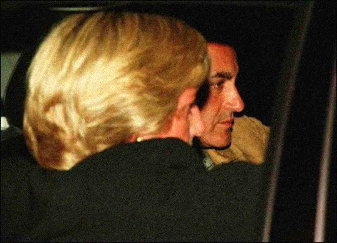 A close-up photo of two people sitting in the backseat of a car at night, with one person’s face mostly hidden and the other’s side profile visible. The lighting is dim and the scene appears candid.