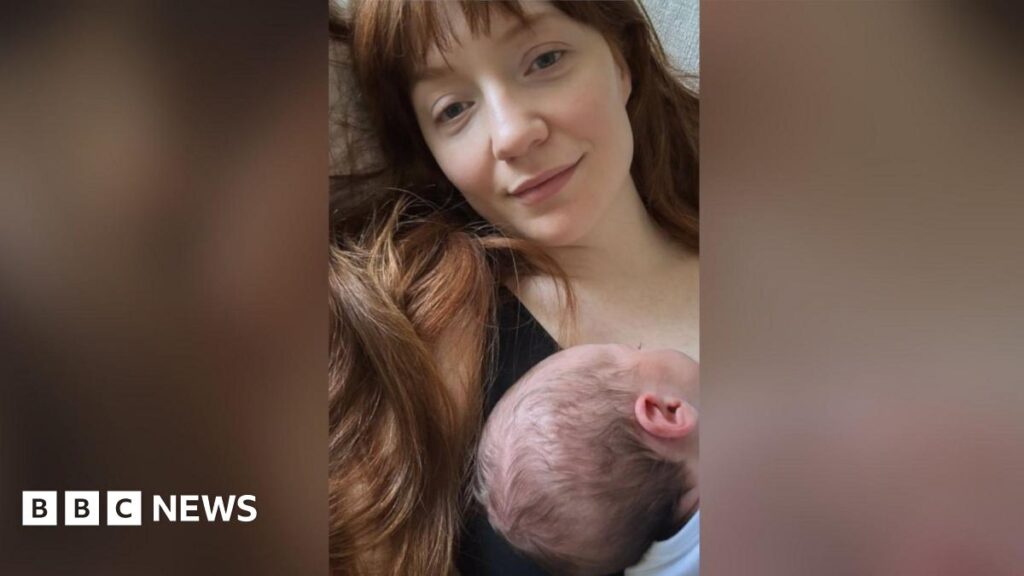 Nicola Roberts, who has long red hair with a fringe, is seen sitting down with her newborn baby on her chest