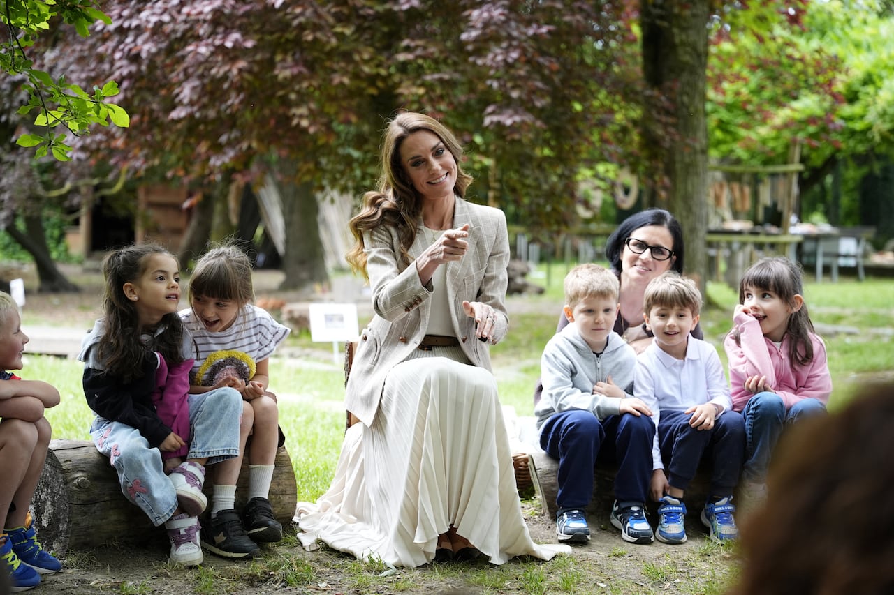 An adult sits in a circle with children.