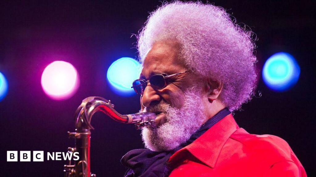 Sonny Rollins: ‘Saxophone colossus’ jazz legend dies aged 95 Sonny Rollins plays saxophone while wearing a red jacket on stage under blue and pink lights.