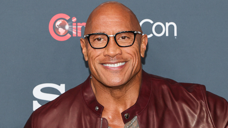 Dwayne Johnson wearing eyeglasses and a brown leather jacket
