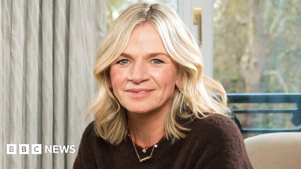 Zoe Ball pictured sitting on an armchair, wearing a brown jumper
