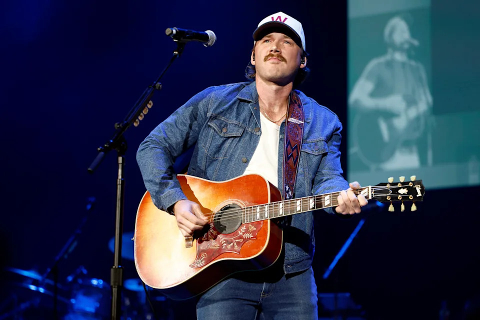 A photo of Morgan Wallen performing onstage with a guitar.