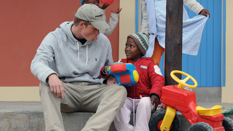 Prince Harry sticks out his tongue as he jokes with a child during a visit to the Lesotho Child Counselling Unit on July 9, 2008 in Maseru, Lesotho.