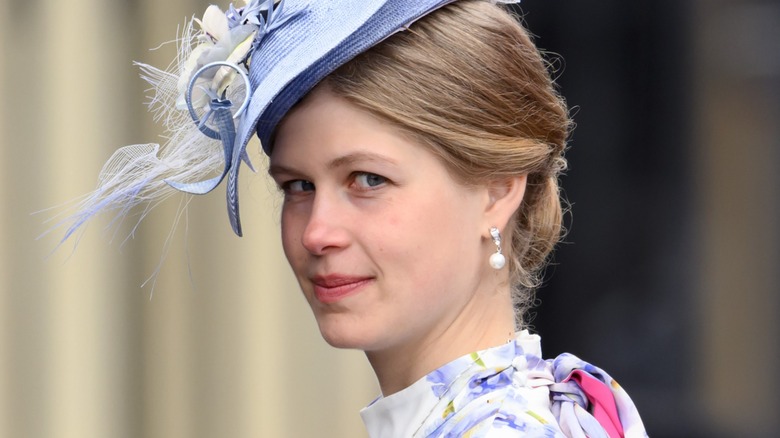 Lady Louise Windsor looking over her shoulder wearing a light blue dress and hat