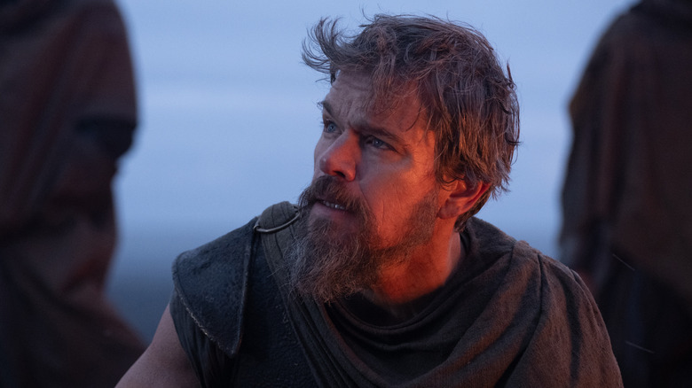 Matt Damon as Odysseus sitting by a campfire in The Odyssey