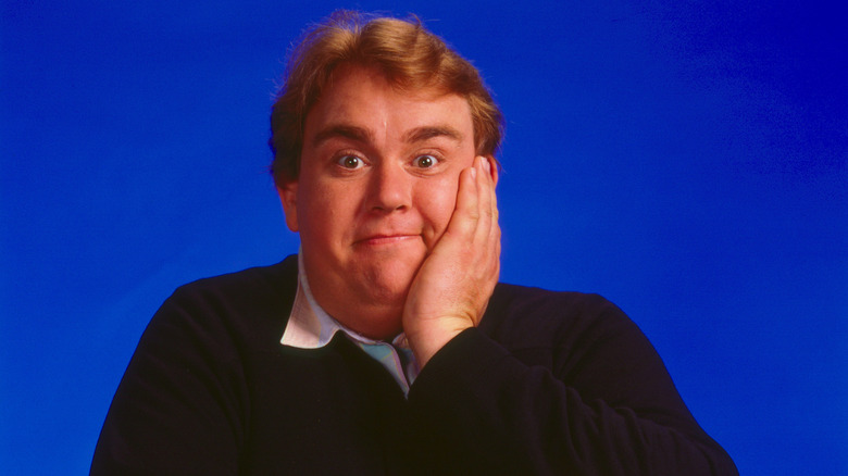 A portrait of John Candy against a blue background