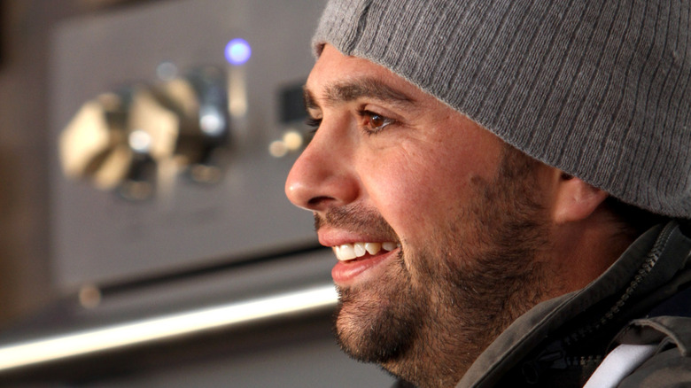 Side profile of chef Jon Shook smiling with a beanie on his head