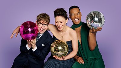 Three people, Josh, Emma and Johannes, smile and laugh as they sit together holding colourful glitterballs