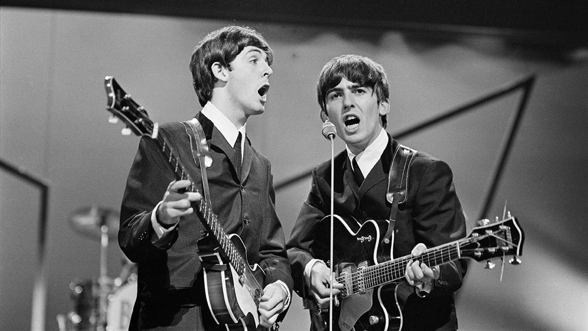 Paul McCartney and George Harrison performing on stage at the London Palladium