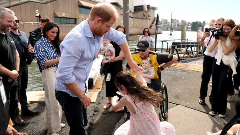 Prince Harry, Duke of Sussex twirls Charlotte, daughter of veteran Joel Vanderzwan as Meghan, Duchess of Sussex looks on at a sailing event with members of Invictus Australia in Sydney Harbour, on day four of the royal trip on April 17, 2026 in Sydney, Australia. The royal couple are on a four-day visit to Australia, with engagements across Melbourne, Canberra and Sydney.