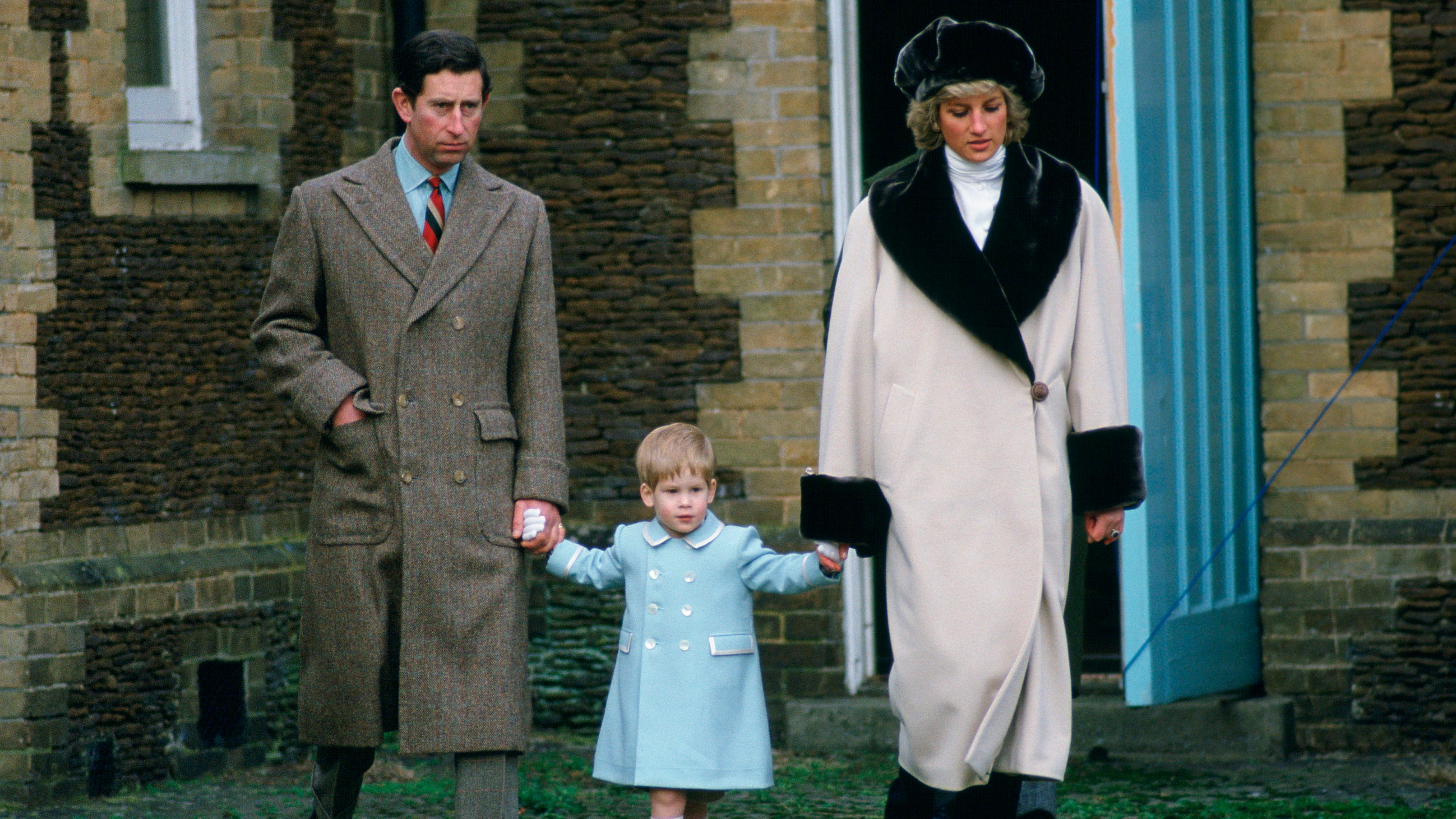 King Charles and Princess Diana hold Prince Harry's hand as they arrive for a photocall at Sandringham