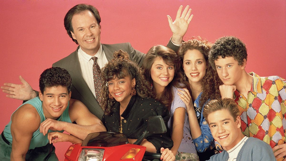 Mario Lopez as A.C. Slater and cast members of Saved by the Bell pose together