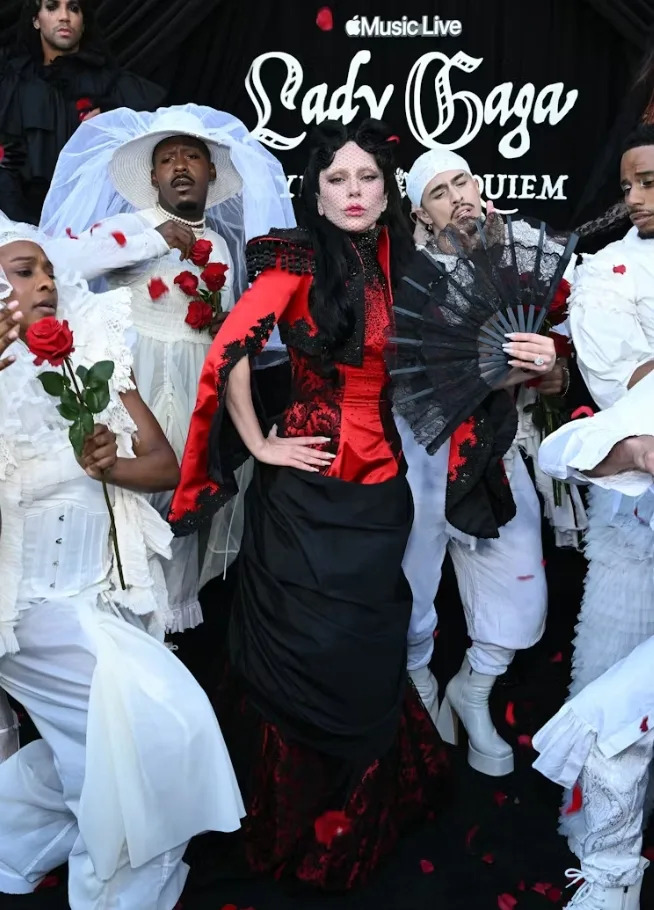 Lady Gaga's dramatic red and black outfit pairs structured details with theatrical styling elements.