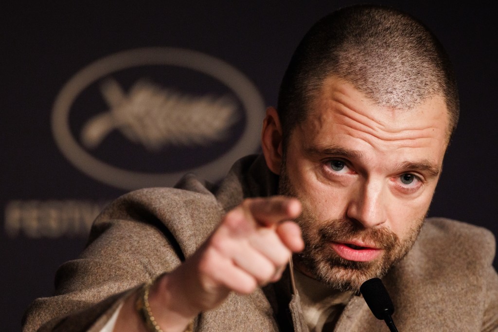 Sebastian Stan pointing a finger while speaking at a press conference.