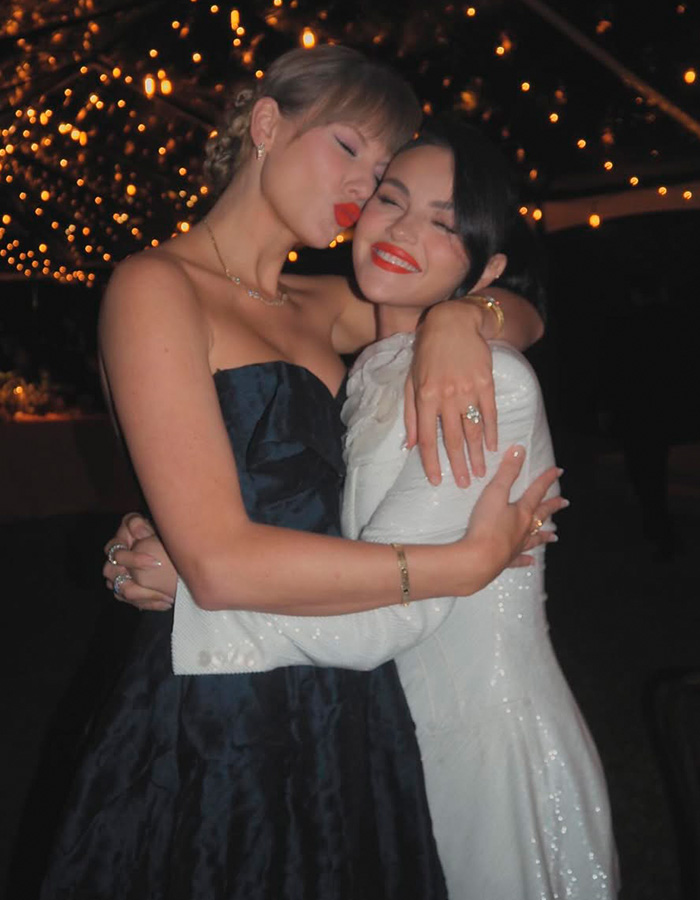 Taylor Swift hugging a friend at a warmly lit event, both smiling