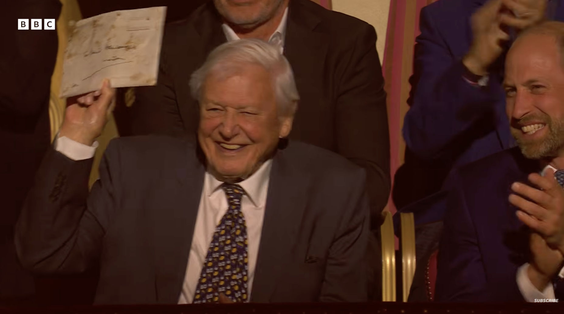 Sir David Attenborough holding an envelope while Prince William claps next to him