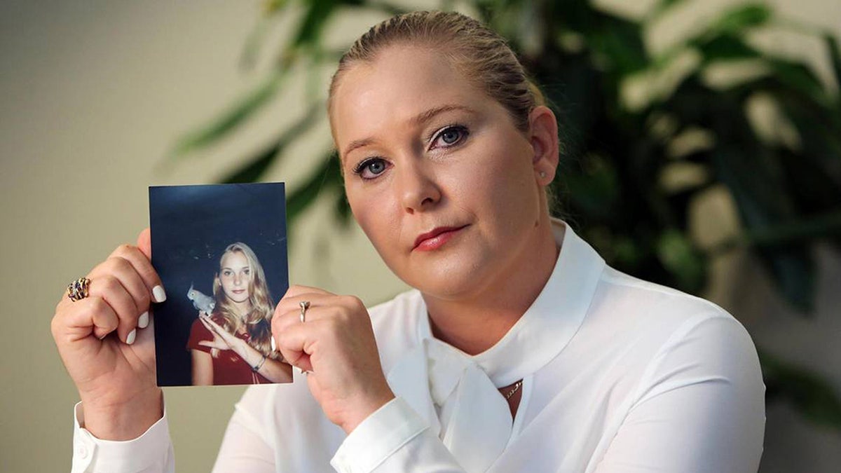Virginia Roberts Giuffre holding a photo of herself as a teen and wearing a white turtleneck