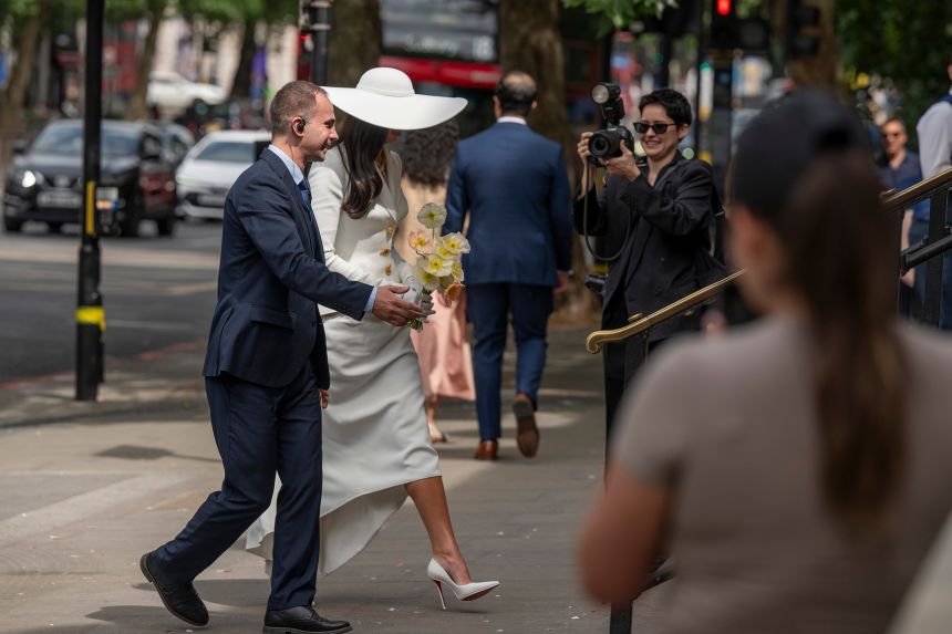 Dua Lipa walks into Old Marylebone Town Hall in a Schiaparelli skirt suit reminiscent of Bianca Jagger.