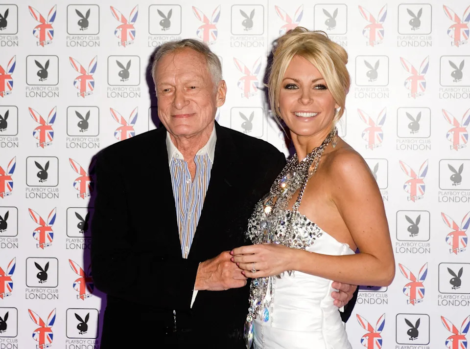 A man and a woman on a red carpet; the woman is wearing a strapless dress with a jeweled bodice