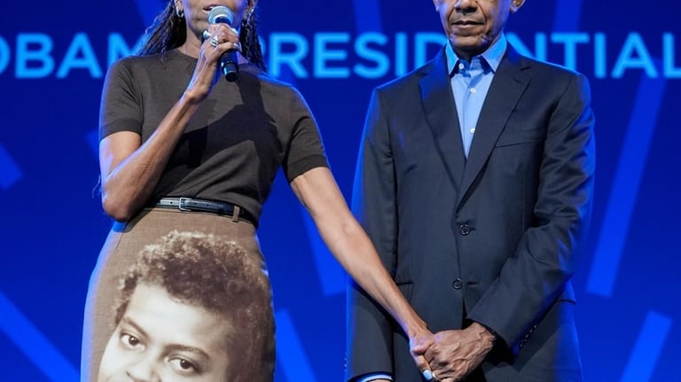 Former President Barack Obama stands on stage with former first...