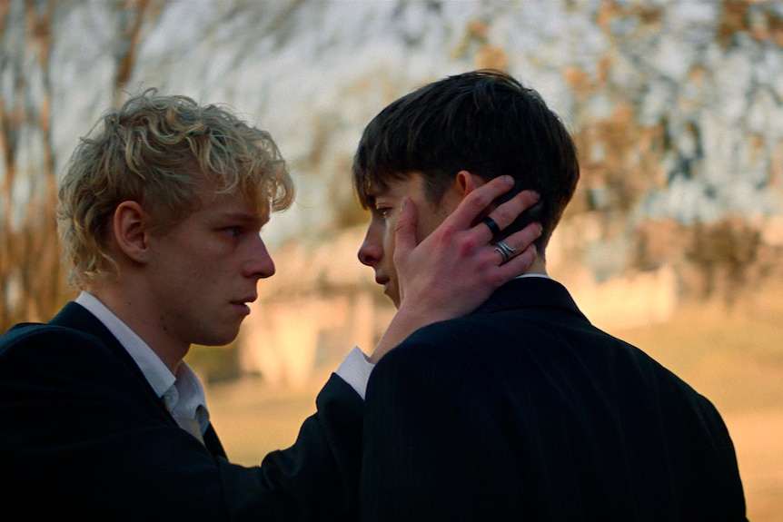 A young man holds another young man by the head
