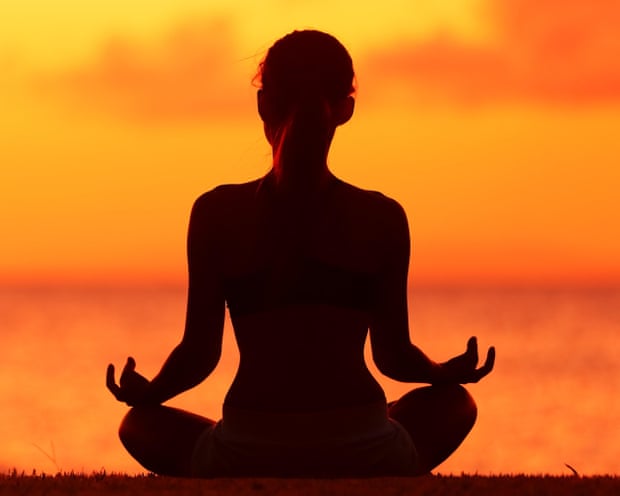 A silhouette of a woman doing yoga at sunset