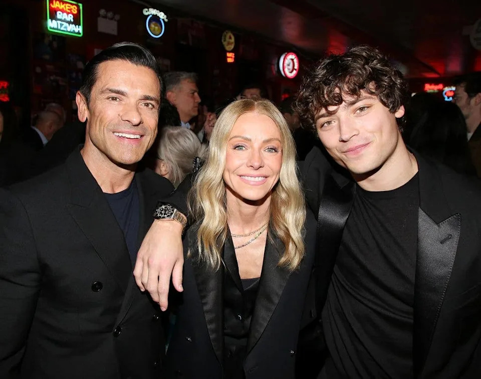 photo of kelly ripa standing between mark consuelos and joaquin consuelos smiling for photo