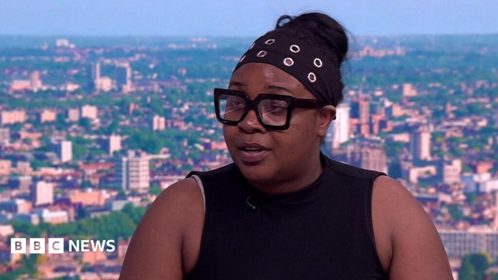 EastEnders: Denise Fox blood cancer storyline welcomed by charity A woman in a black armless dress with a black band on her head sitting in a TV studio being interviewed.
