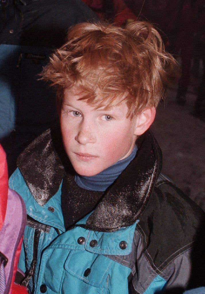 Young Prince Harry with red hair, wearing a blue and black winter jacket.