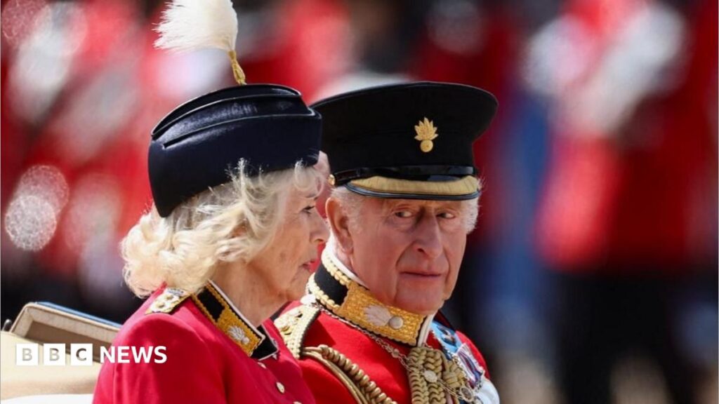 In pictures: Trooping the Colour marks King’s official birthday Princess Charlotte and Prince George ride in a carriage with a tan interior. She is wearing a white dress with a white bow in her hair and is smiling. He is wearing a dark suit with a white shirt and a light blue tie.